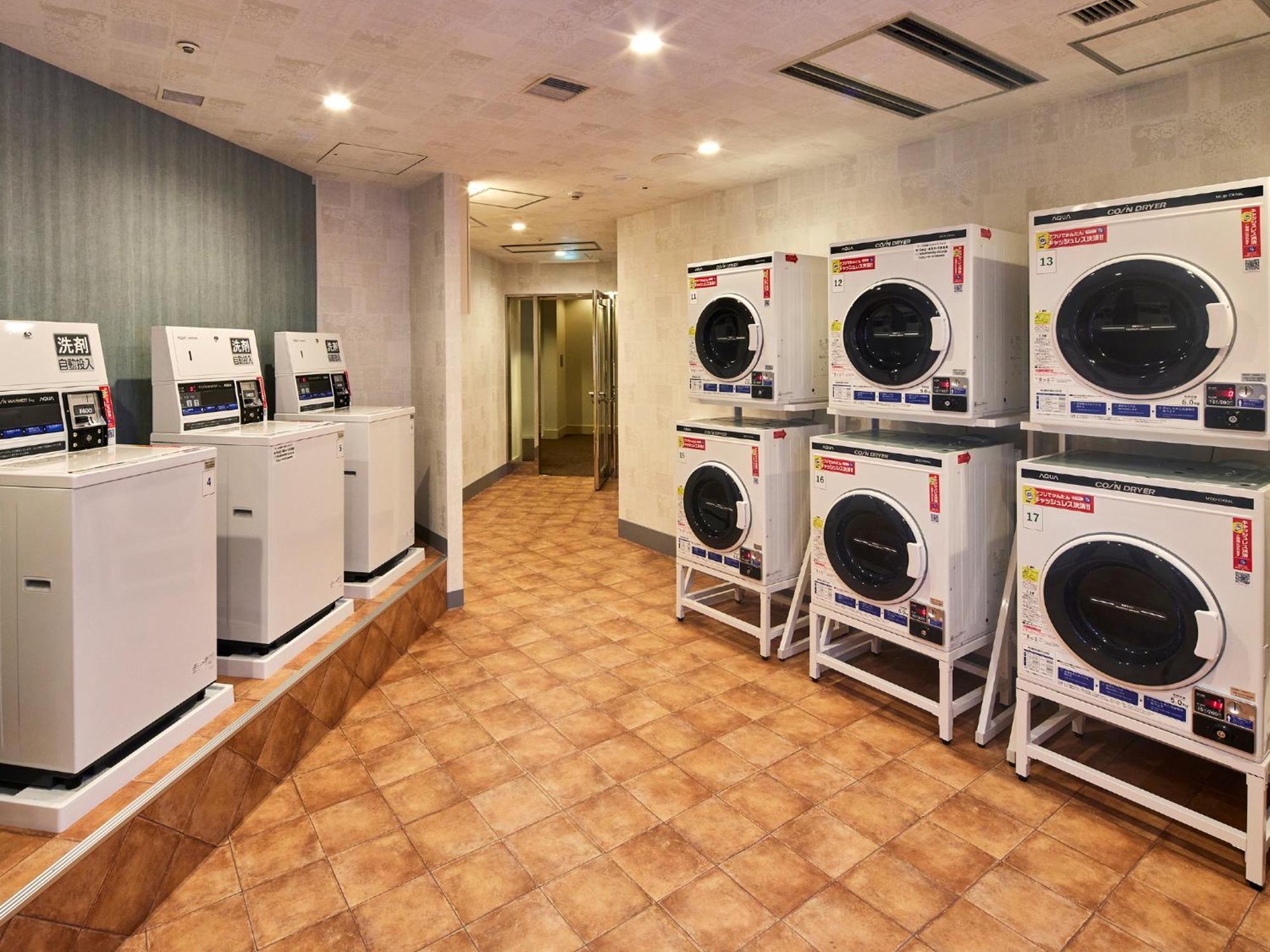 فندق Grand Nikko Tokyo Bay Maihama Urayasu المظهر الخارجي الصورة The photo shows a laundry room with several washing machines and dryers. On the left side, there are five white washing machines, and on the right side, there are four dryers. The machines are arranged in a clean, tiled space with a neutral-colored w