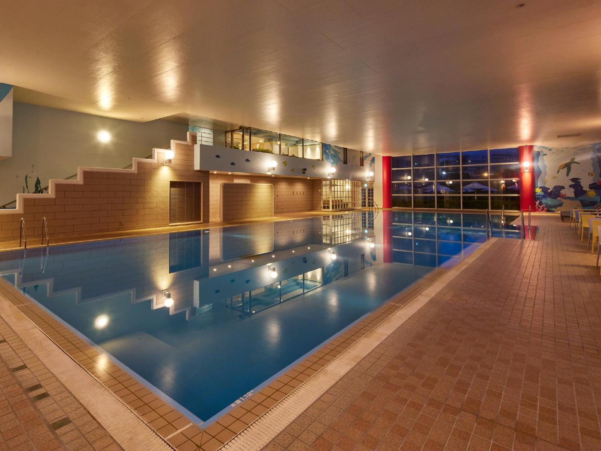 فندق Grand Nikko Tokyo Bay Maihama Urayasu المظهر الخارجي الصورة The photo shows an indoor swimming pool area. The pool features a calm blue water surface and is surrounded by tiled flooring. There is a staircase leading to a higher level, likely providing access to a lounge or seating area. Large windows allow na